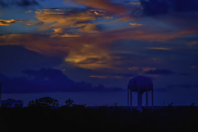 Silhouette trees against dramatic sky during sunset