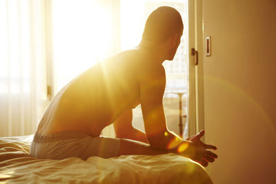 Man sitting on bed with sunlight through window