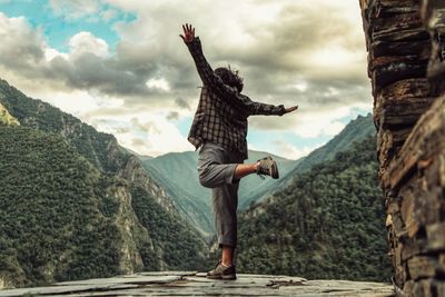 Woman standing on one leg against mountains