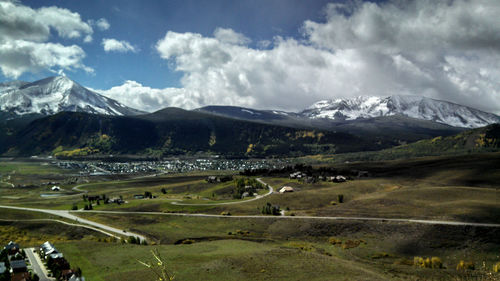 Scenic view of landscape by mountains against sky