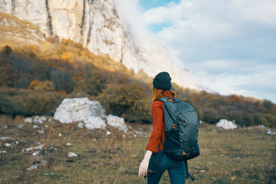 Rear view of man standing on mountain against sky