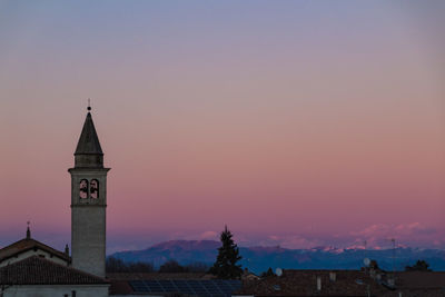 Tower amidst buildings against sky during sunset