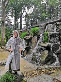 Portrait of smiling man standing by waterfall