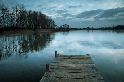 Cloudy winter evening, freezing lake with a pier