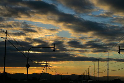 Low angle view of silhouette street lights against dramatic sky