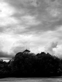 Silhouette building by river against sky