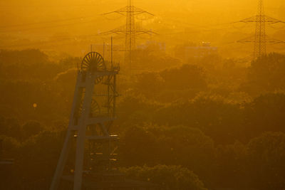 Electricity pylon on field against sky during sunset