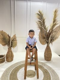 Cute boy sitting by palm tree