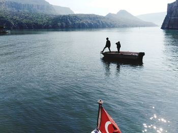 Man standing with son in boat on lake