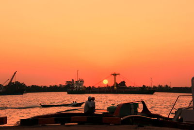 Silhouette man by sea against sky during sunset