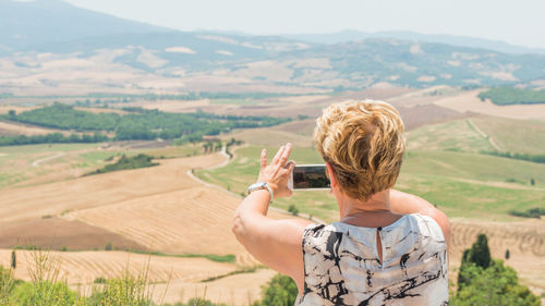 Rear view of woman photographing on field