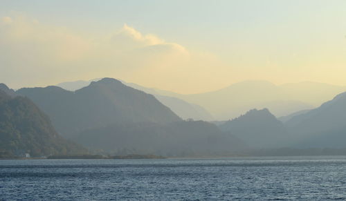 Scenic view of sea and mountains against sky during sunset