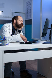 Exhausted doctor using computer in clinic