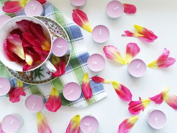 High angle view of petals and candles on white background