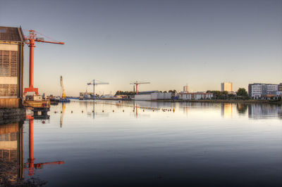 Cranes at harbor against clear sky