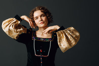 Portrait of young woman drinking water against black background