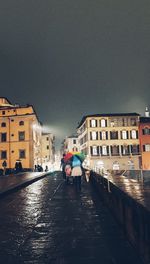 Rear view of people walking on wet street in city