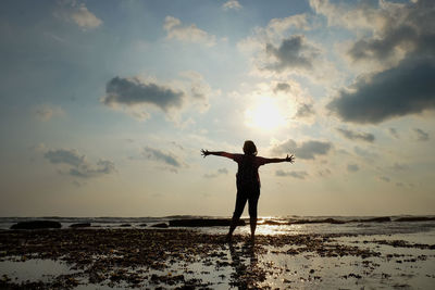 Silhouette man standing on beach against sky during sunset