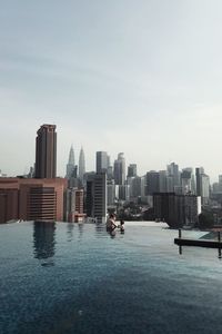 Buildings by swimming pool in city against sky