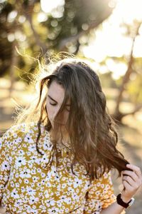 Teenage girl holding long brown hair while standing outdoors