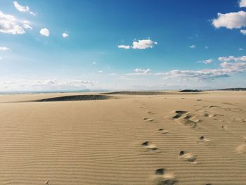 Footprints on desert against sky