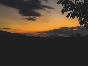 Scenic view of silhouette mountains against orange sky