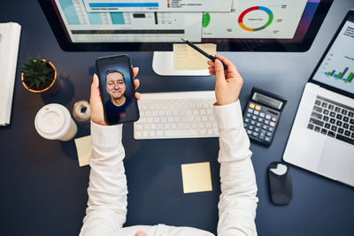 Businesswoman having video call on smartphone. woman working with data on charts on computer screen