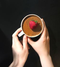 Close-up of woman holding ice cream cone against black background