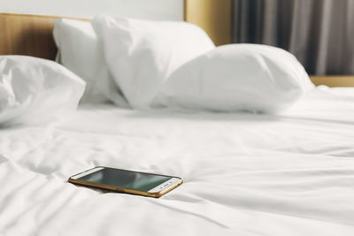 Close-up of mobile phone on bed