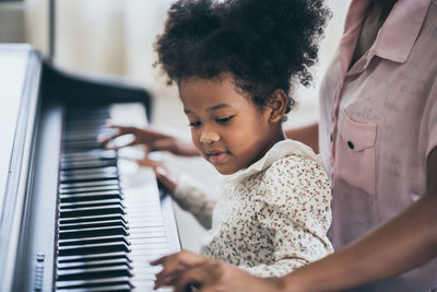 Midsection of woman playing piano with daughter