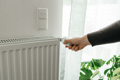 A man regulates the temperature on the radiator at home. rising prices for heating in households. 