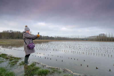 Woman standing on snow covered field against sky