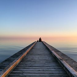 Pier over sea against clear sky during sunset