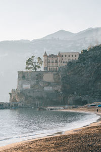 Buildings by sea against sky