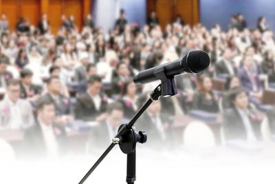 Close-up of microphone with people in background at conference
