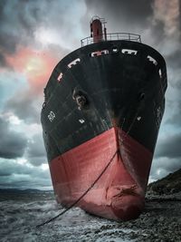 Low angle view of abandoned ship on beach against sky