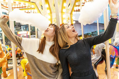 Couple of young multi-ethnic women eating cotton candy at a party. concept of millennial generation