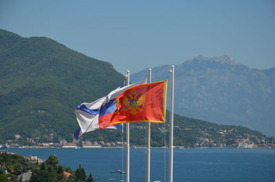 Flag on boat in sea against mountains