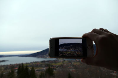 Midsection of man using mobile phone against sky