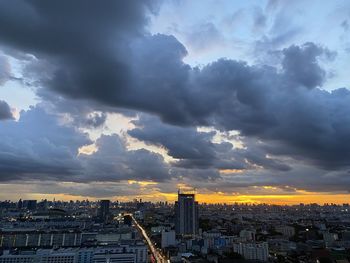 Aerial view of city against cloudy sky during sunset