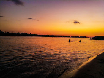 Silhouette people on beach against sky during sunset