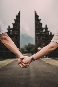 Cropped image of people holding hands against bali gate