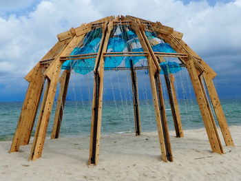 Wooden structure on beach against sky