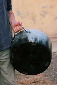 Midsection of man holding kitchen utensil outdoors