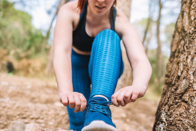 Low section of woman tying shoelace