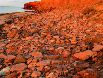 Stone wall by sea against orange sky