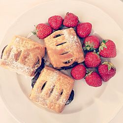 High angle view of puff pastries with strawberries in plate