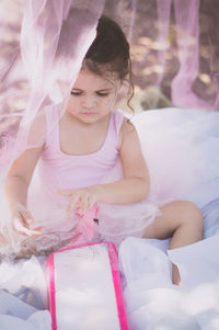 Rear view of smiling girl sitting on bed