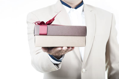 Midsection of man holding umbrella against white background