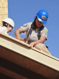 Low angle view of man working against blue sky